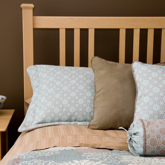 Elegant blue and brown bed pillows and linens in a modern master bedroom.